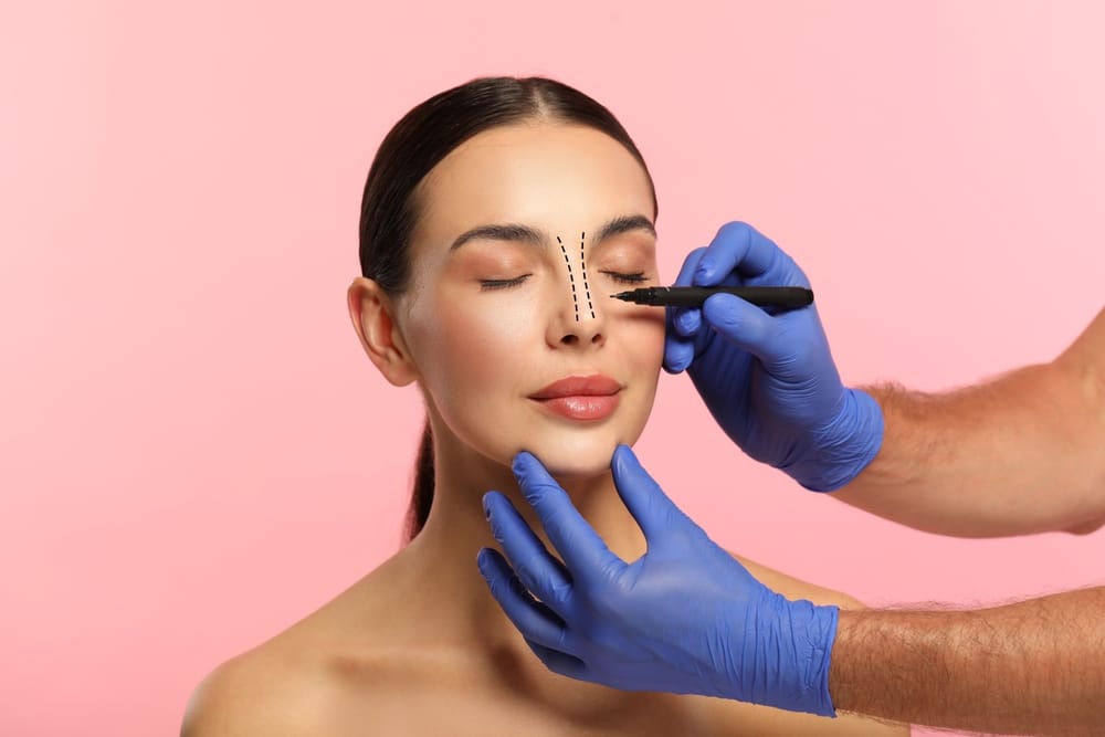 Woman having her nose drawn on by her surgeon in preparation for her rhinoplasty procedure. Woman having her nose drawn on by her surgeon in preparation for her rhinoplasty procedure.